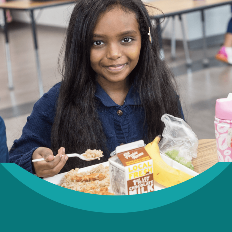 smiling young girl eating school lunch