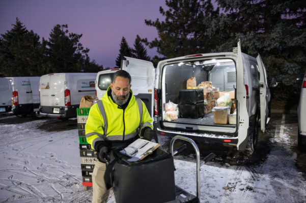 Delivery driver loading bags of food into van