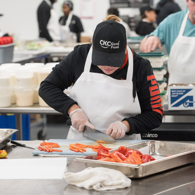 Food service team member chopping fresh bell peppers