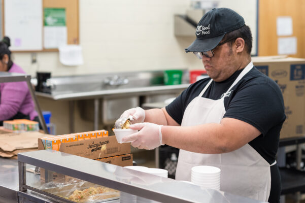 Food service worker serving kids in a cafeteria line