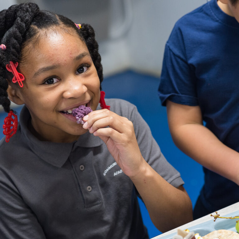 Smiling young girl eating purple cauliflower