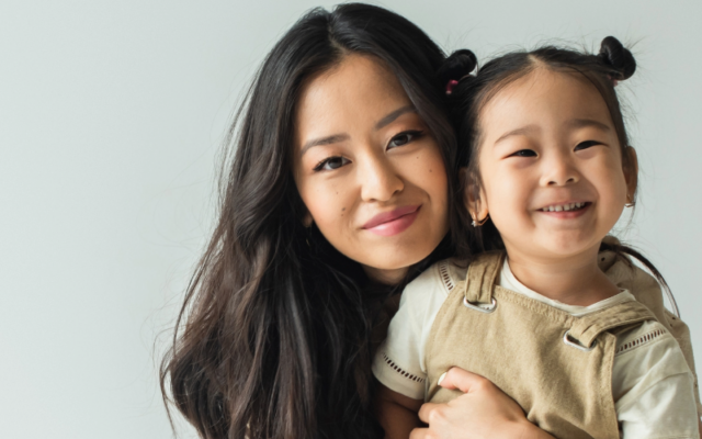 Smiling Asian woman posing with toddler daughter